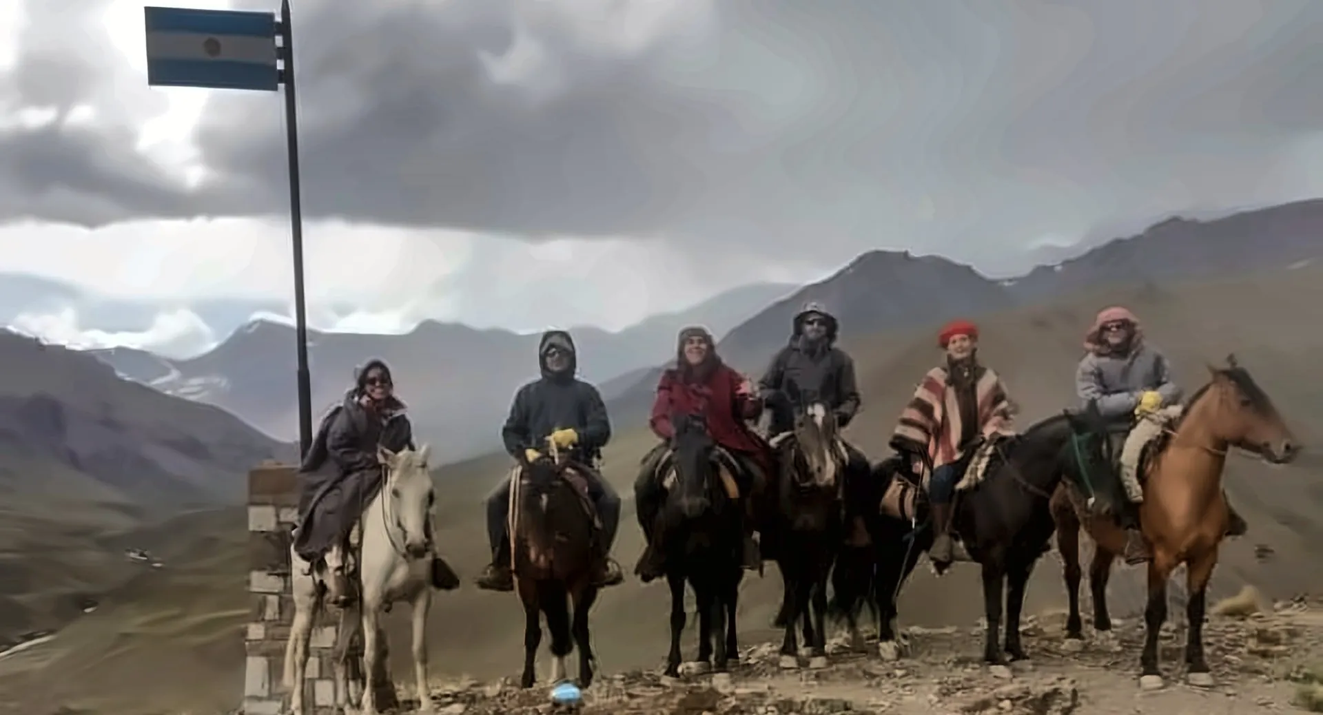Julia y su grupo a caballo junto a la bandera argentina, en la cordillera
